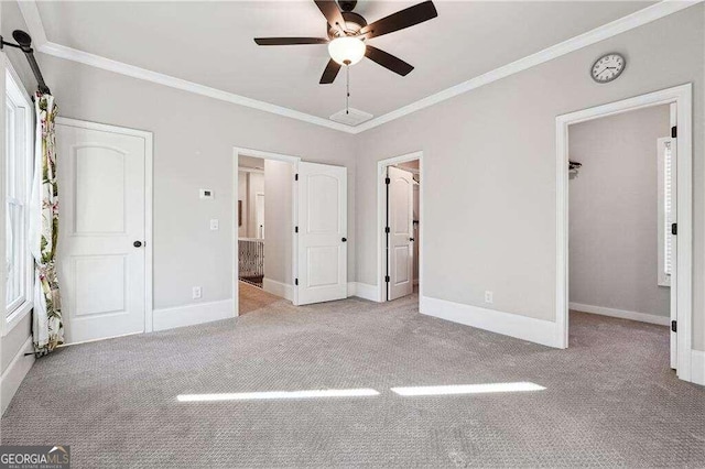 unfurnished bedroom featuring light carpet, multiple windows, ceiling fan, and crown molding