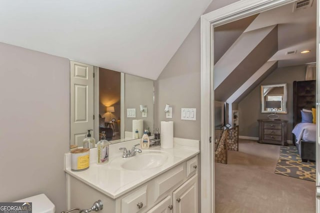 bathroom with toilet, vanity, and vaulted ceiling