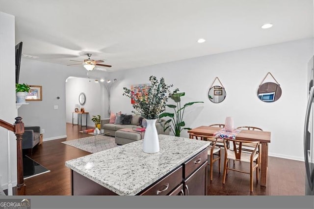 kitchen with dark brown cabinetry, ceiling fan, a center island, and dark hardwood / wood-style floors