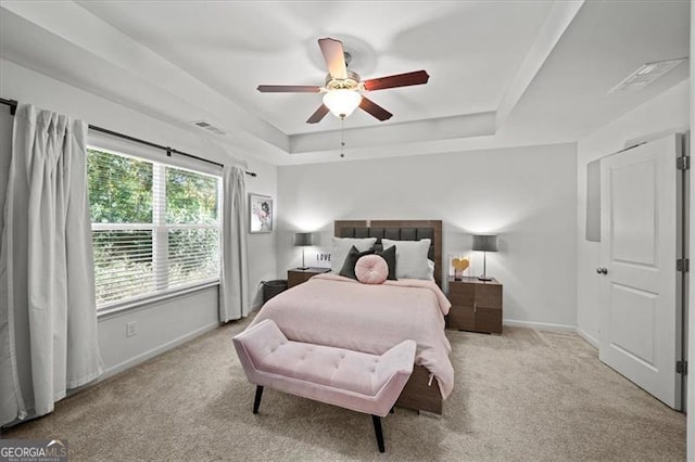 bedroom featuring a tray ceiling, ceiling fan, and light carpet