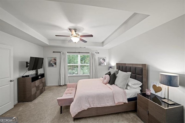 carpeted bedroom featuring a raised ceiling and ceiling fan