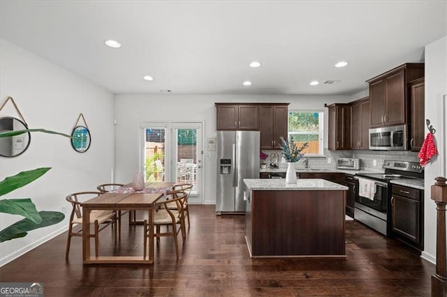 kitchen featuring stainless steel appliances, a kitchen island, plenty of natural light, and dark wood-type flooring