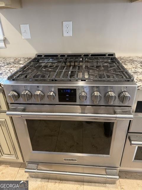 details with cream cabinetry, double oven range, and light stone counters