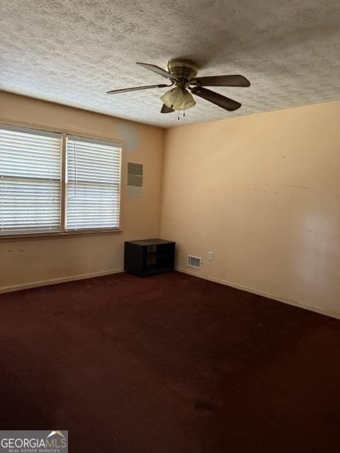 spare room with carpet flooring, ceiling fan, and a textured ceiling