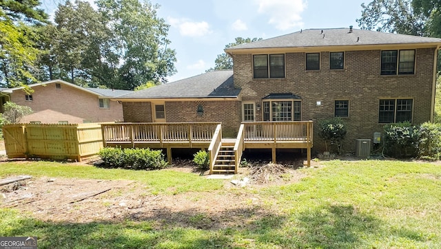 rear view of property featuring a deck, a yard, and central AC