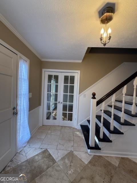 foyer with french doors, a textured ceiling, and ornamental molding