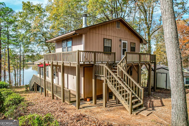 rear view of property featuring a shed and a deck with water view