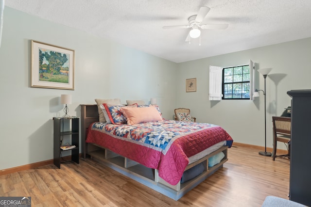 bedroom featuring ceiling fan, a textured ceiling, and light wood-type flooring