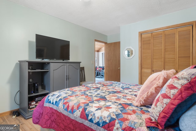 bedroom with wood-type flooring, a textured ceiling, and a closet