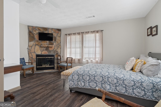 bedroom featuring a fireplace, ceiling fan, and dark hardwood / wood-style flooring