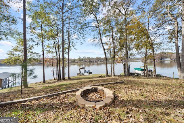 view of yard featuring a dock, a water view, and a fire pit