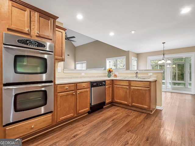 kitchen featuring pendant lighting, sink, dark hardwood / wood-style flooring, kitchen peninsula, and stainless steel appliances