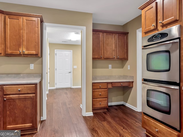 kitchen with dark hardwood / wood-style flooring, built in desk, and double oven