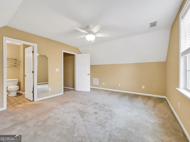 unfurnished bedroom featuring a walk in closet, light colored carpet, ceiling fan, and lofted ceiling