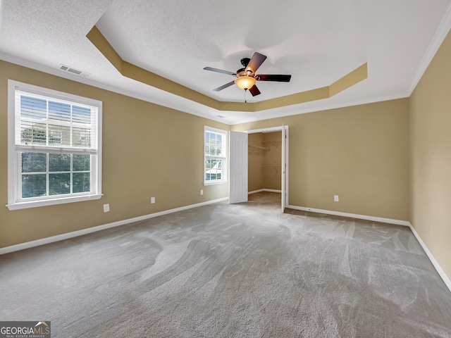 unfurnished bedroom featuring ceiling fan, a walk in closet, crown molding, and multiple windows