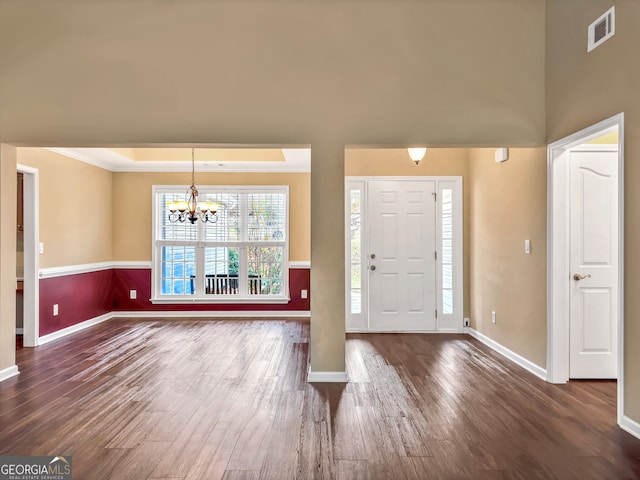 foyer entrance featuring crown molding, dark hardwood / wood-style floors, and an inviting chandelier