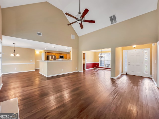 unfurnished living room featuring high vaulted ceiling, dark wood-type flooring, and ceiling fan with notable chandelier