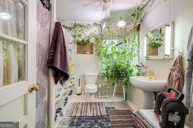 bathroom with ceiling fan, toilet, and tile walls