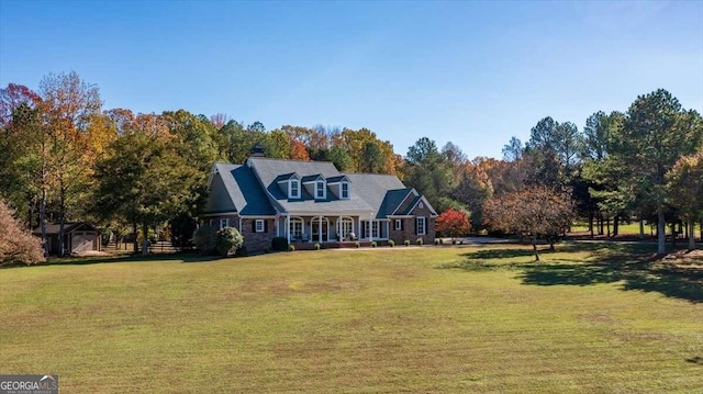 new england style home featuring covered porch and a front yard