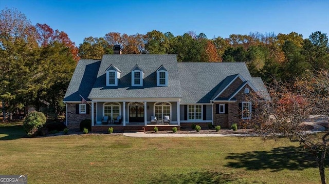 cape cod home with a front yard and a porch