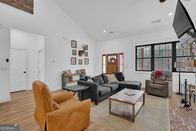 living room featuring high vaulted ceiling and light wood-type flooring