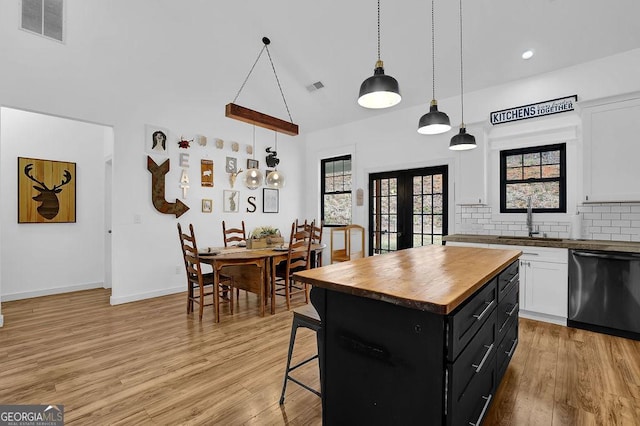 kitchen featuring dishwasher, a kitchen island, pendant lighting, and white cabinets