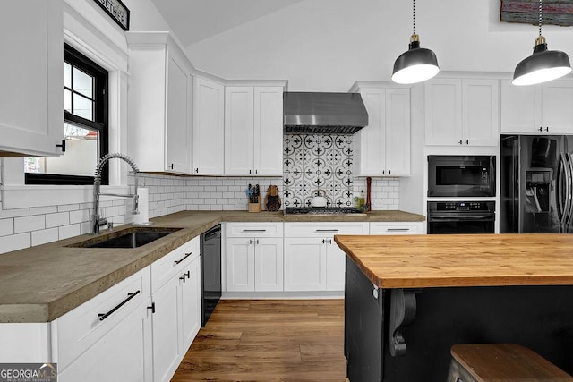 kitchen featuring white cabinets, wall chimney exhaust hood, butcher block countertops, and black appliances