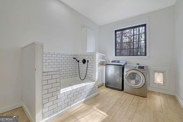 washroom featuring cabinets, light wood-type flooring, and washer and clothes dryer