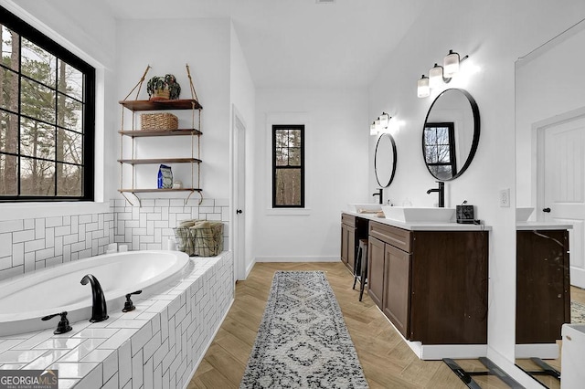 bathroom featuring vanity, plenty of natural light, and tiled bath