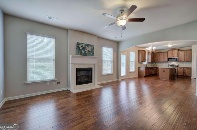 unfurnished living room featuring ceiling fan with notable chandelier and dark hardwood / wood-style floors