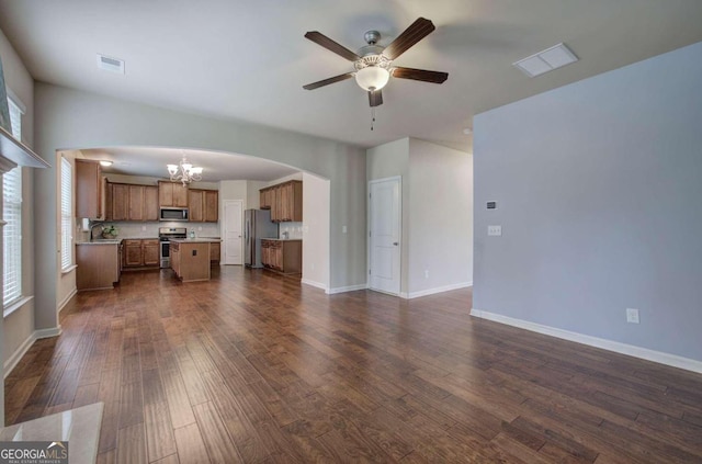 unfurnished living room featuring ceiling fan with notable chandelier and dark hardwood / wood-style flooring