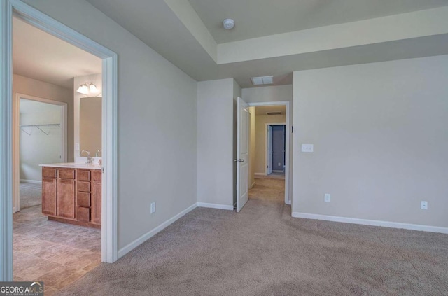 unfurnished bedroom featuring light colored carpet, sink, a spacious closet, a notable chandelier, and a closet