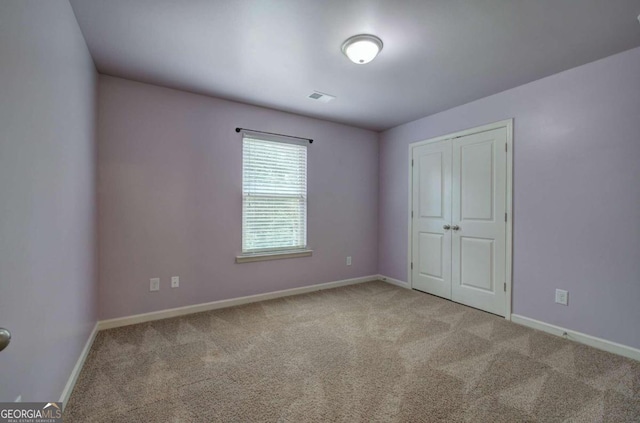 unfurnished bedroom featuring light carpet and a closet