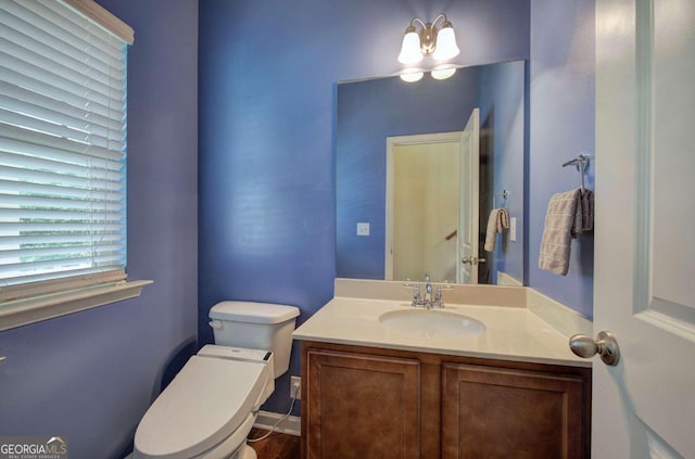 bathroom with toilet, vanity, and an inviting chandelier