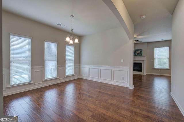 empty room with dark hardwood / wood-style flooring and ceiling fan with notable chandelier