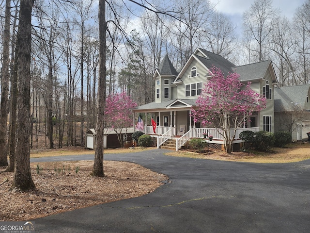 victorian house featuring an outbuilding, covered porch, and driveway