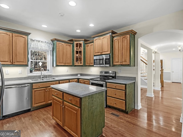 kitchen featuring arched walkways, dark wood finished floors, stainless steel appliances, recessed lighting, and a sink