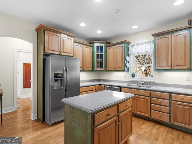 kitchen featuring arched walkways, stainless steel appliances, recessed lighting, light wood-style floors, and a sink