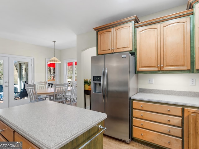 kitchen with french doors, hanging light fixtures, a kitchen island, light wood-type flooring, and stainless steel fridge