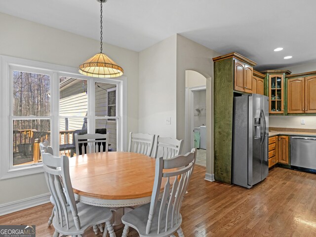 dining area with arched walkways, recessed lighting, light wood-type flooring, and baseboards