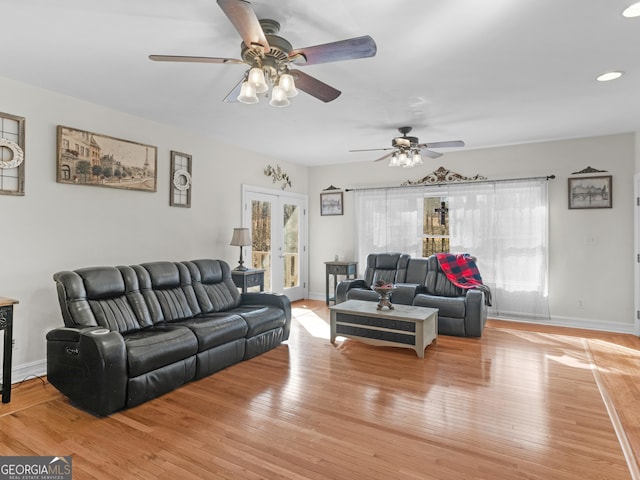 living area featuring light wood finished floors, baseboards, and a ceiling fan