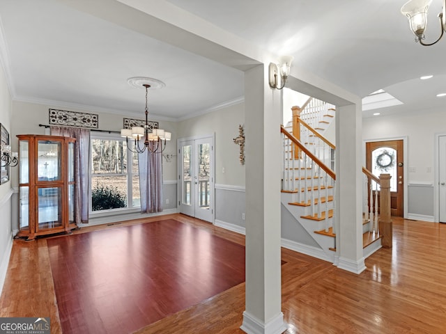 unfurnished dining area featuring wood-type flooring, ornamental molding, and a chandelier