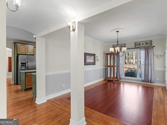 unfurnished dining area featuring crown molding, a chandelier, and wood finished floors