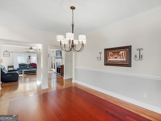 dining area featuring baseboards, ceiling fan with notable chandelier, wood finished floors, and crown molding