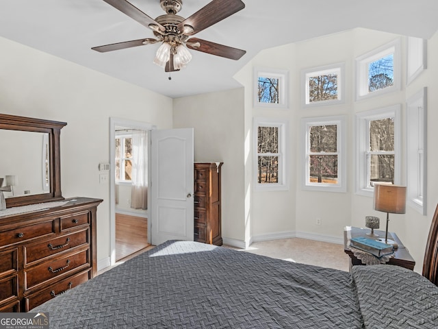 bedroom featuring light carpet, a ceiling fan, and baseboards