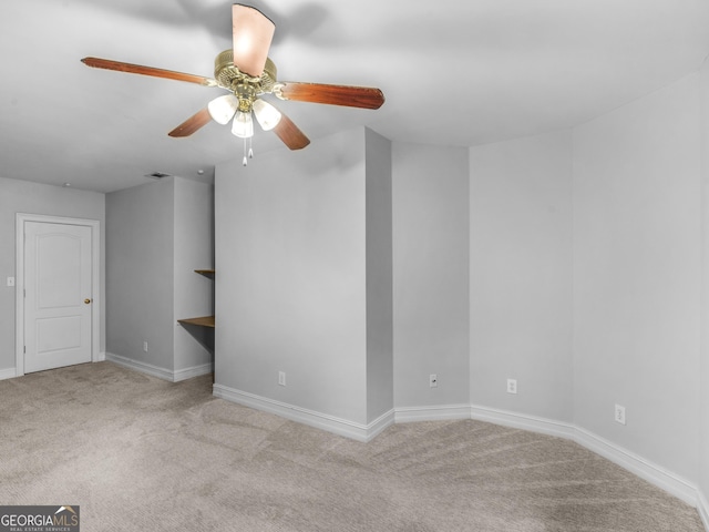 carpeted spare room featuring baseboards, visible vents, and ceiling fan