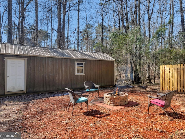 view of yard with an outbuilding, fence, a fire pit, and a shed