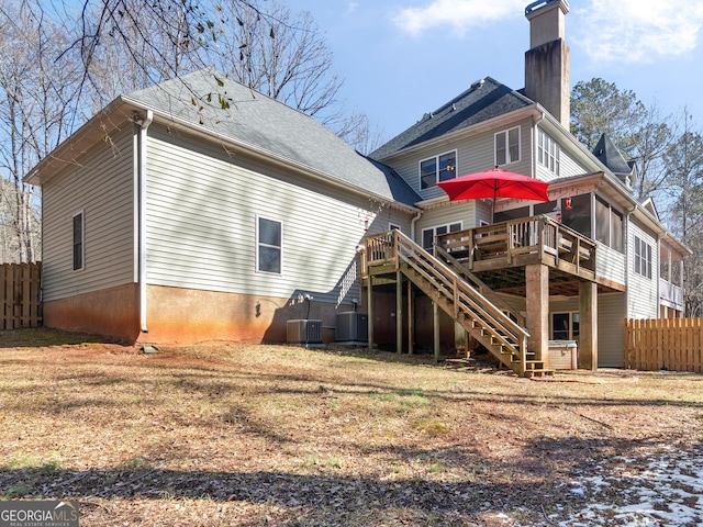 rear view of house featuring stairs, a deck, a chimney, and fence