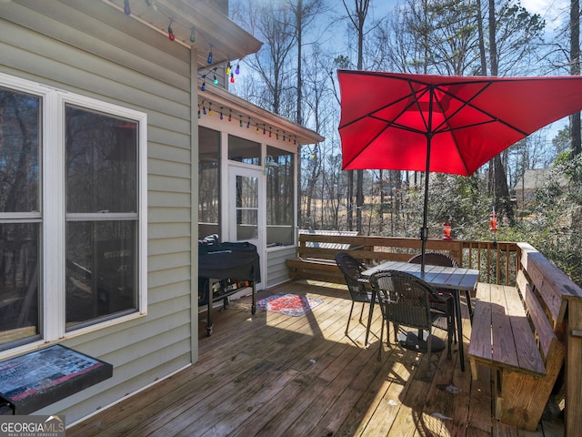 wooden deck with a sunroom and area for grilling