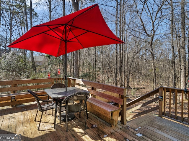 deck featuring a wooded view and outdoor dining space